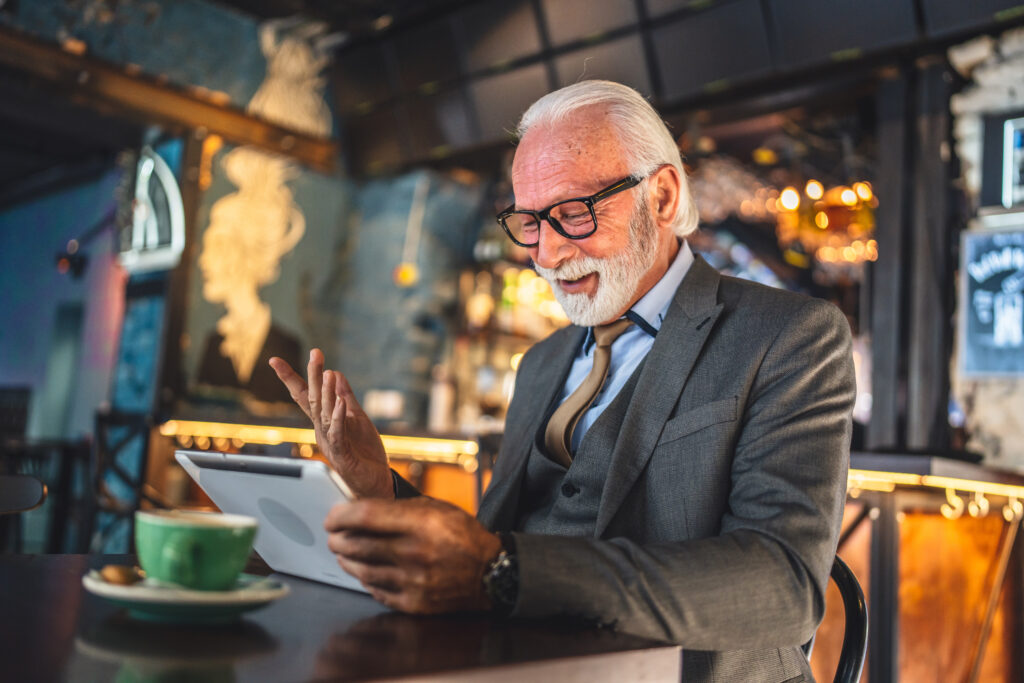 One Senior man caucasian male businessman business owner use digital tablet sit at cafe